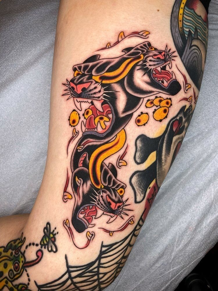 Photograph of a bicep with a tattoo of a flaming, multi-headed tiger