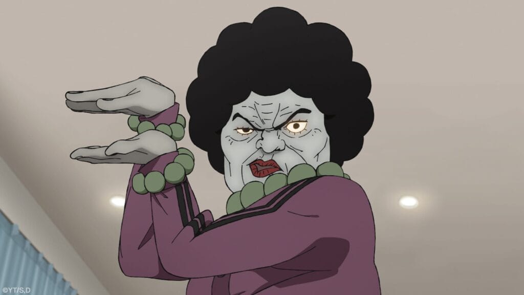 Still from Dan Da Dan: Evil Eye that depicts an older, black-haired woman wearing a pink tracksuit and green beads. Her eyes are glowing yellow as they pose with a sneer on her face