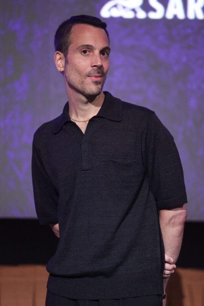Photograph of director Abel Góngora, wearing a dark polo and posing in front of a screen that reads "Science SARU"